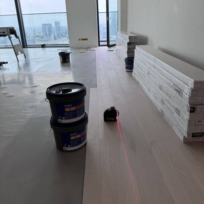 Verlegung von Landhausdielen aus Eiche in einer Wohnung mit Blick auf die Frankfurter Skyline