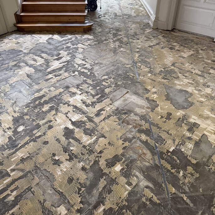 Beschädigtes Fischgrätparkett in der Diele einer Altbauwohnung im Frankfurter Westend vor der Sanierung