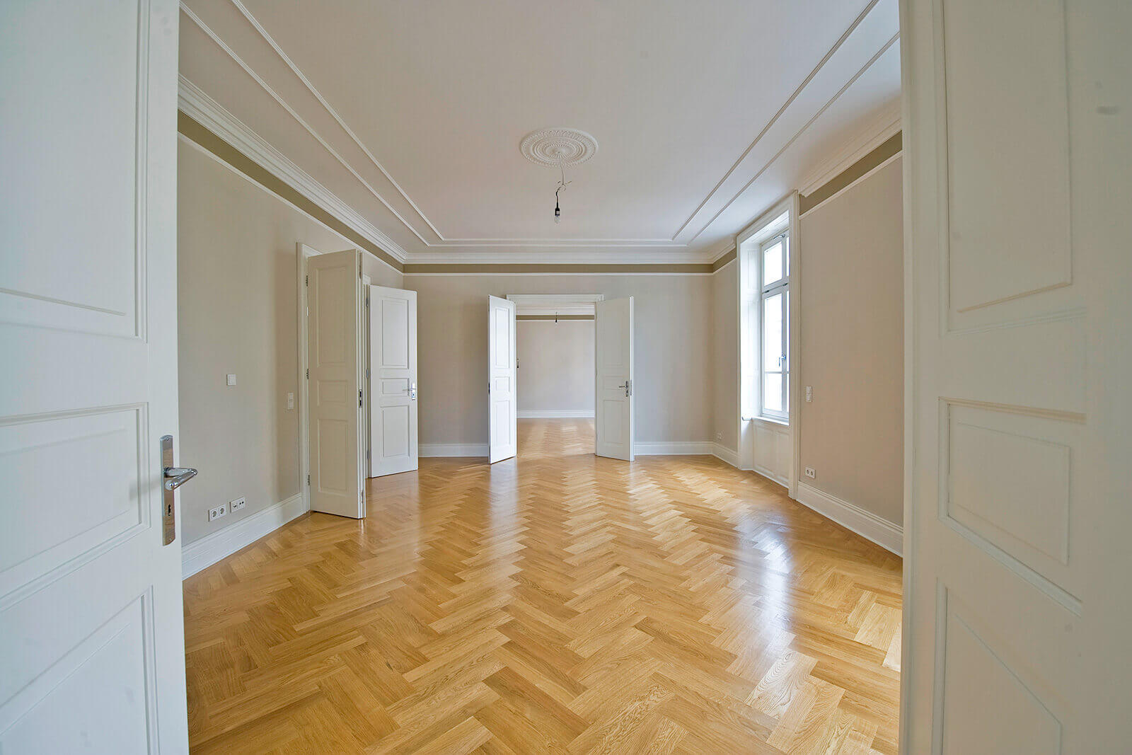 Frisch versiegeltes Fischgrätparkett in einer Frankfurter Altbauwohnung mit Stuckdecke